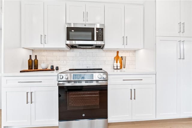 kitchen featuring stainless steel appliances, light countertops, white cabinetry, and decorative backsplash