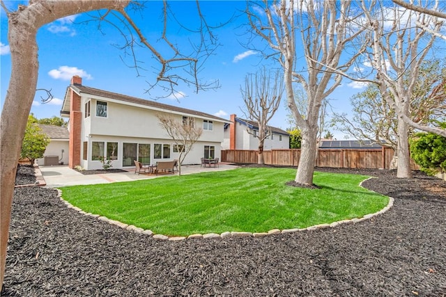 back of property featuring a yard, a patio, a chimney, stucco siding, and fence