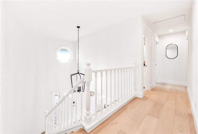 corridor featuring baseboards, wood finished floors, and an upstairs landing