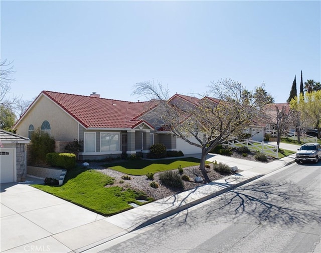 view of front of house featuring a front lawn, a tile roof, concrete driveway, a garage, and a chimney