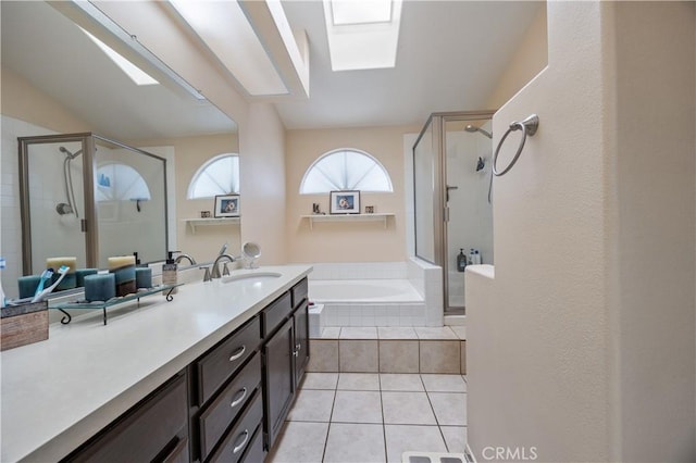 bathroom with vanity, a skylight, tile patterned flooring, a shower stall, and a bath