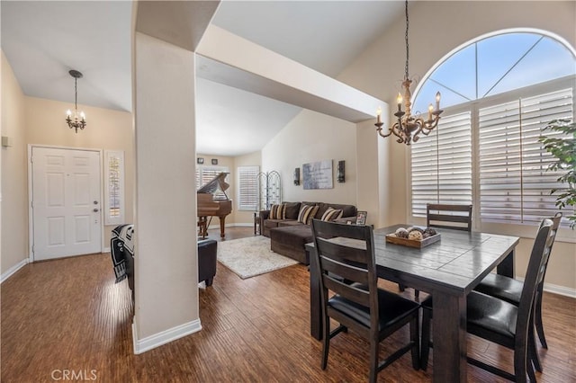 dining space featuring dark wood-type flooring, high vaulted ceiling, baseboards, and a chandelier