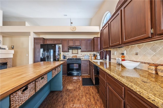 kitchen with black appliances, a sink, wood counters, under cabinet range hood, and backsplash