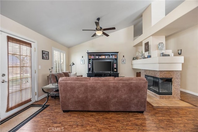 living area featuring lofted ceiling, wood finished floors, baseboards, ceiling fan, and a tile fireplace