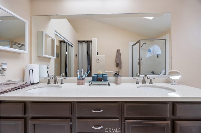 bathroom with vaulted ceiling, double vanity, a stall shower, and a sink