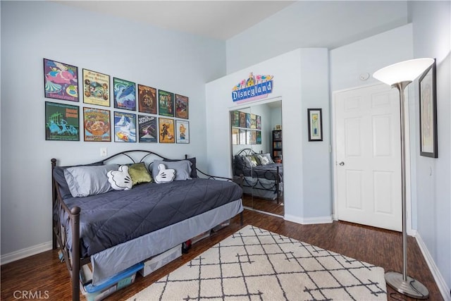 bedroom featuring baseboards, wood finished floors, and vaulted ceiling