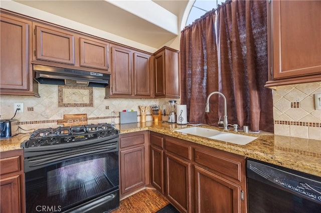 kitchen with black appliances, light stone counters, under cabinet range hood, and a sink