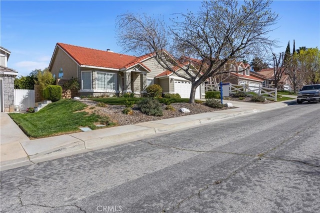 view of front facade featuring driveway, a tile roof, a garage, and fence