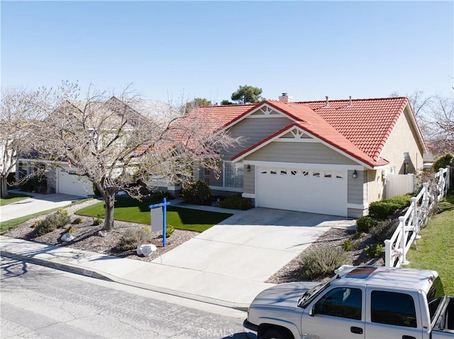 view of front of home with fence, concrete driveway, an attached garage, and a tile roof