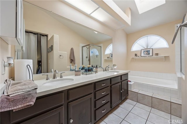 full bath featuring a sink, lofted ceiling with skylight, a garden tub, and tile patterned floors