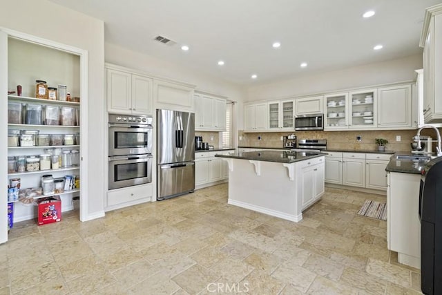 kitchen with visible vents, a center island, stainless steel appliances, a kitchen bar, and a sink