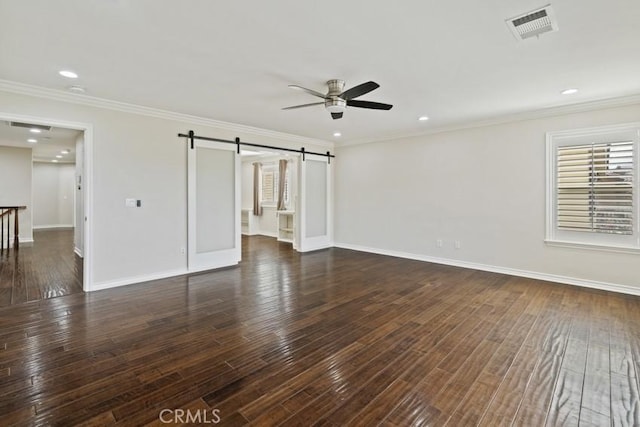 interior space featuring a barn door, visible vents, hardwood / wood-style floors, and ornamental molding