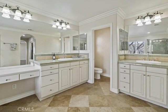 bathroom featuring ornamental molding, two vanities, and a sink