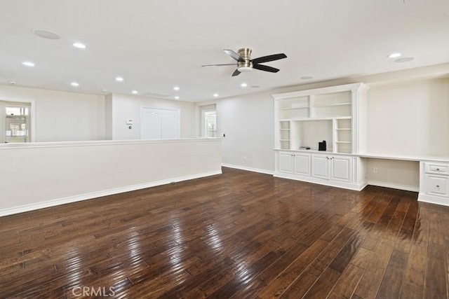 unfurnished living room with baseboards, a ceiling fan, dark wood-style floors, built in desk, and recessed lighting