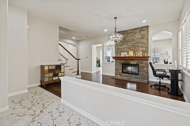 interior space with recessed lighting, a stone fireplace, wood finished floors, baseboards, and stairs