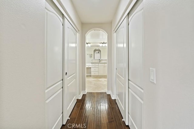 corridor with arched walkways and dark wood-type flooring