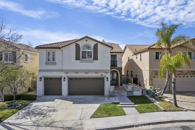 mediterranean / spanish-style house with driveway, an attached garage, a tiled roof, and stucco siding