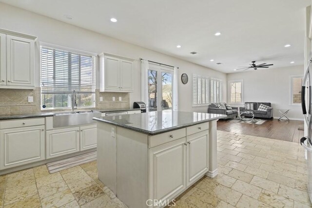 kitchen with tasteful backsplash, recessed lighting, a sink, and a center island