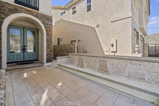 exterior space with stone siding, french doors, a patio, and stucco siding