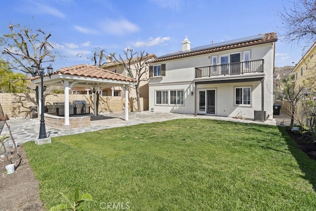 back of property featuring a yard, a gazebo, roof mounted solar panels, a patio area, and a fenced backyard