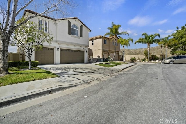 view of front of house with an attached garage, a tile roof, concrete driveway, and stucco siding