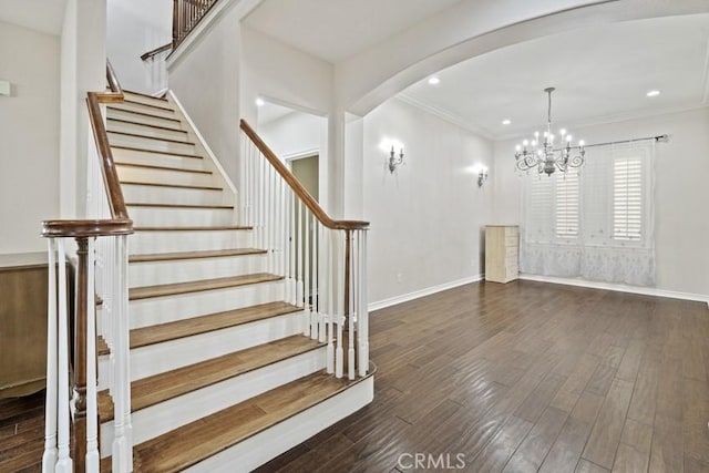 staircase featuring ornamental molding, arched walkways, baseboards, and wood finished floors