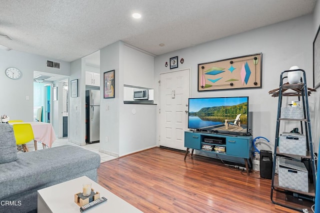 living area with a textured ceiling, wood finished floors, and visible vents