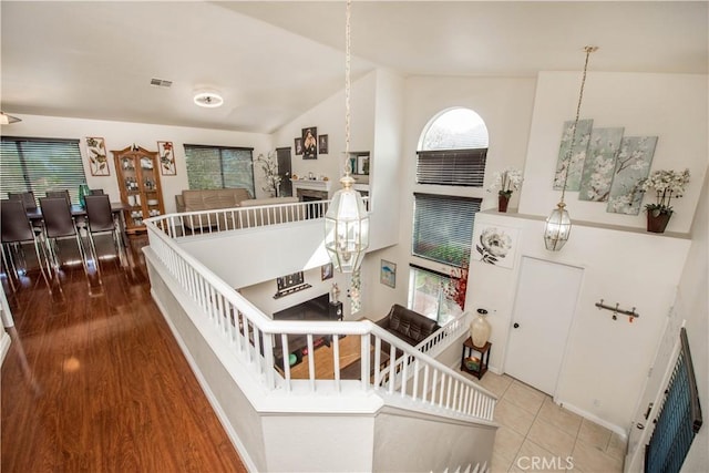 interior space with high vaulted ceiling, a fireplace, visible vents, and wood finished floors