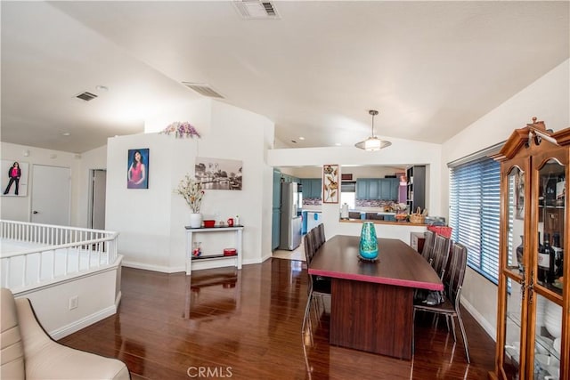 dining room featuring visible vents, vaulted ceiling, and wood finished floors