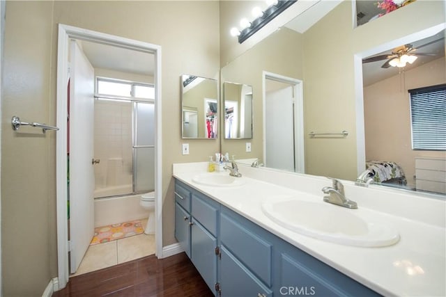 bathroom with double vanity, a sink, toilet, and ceiling fan