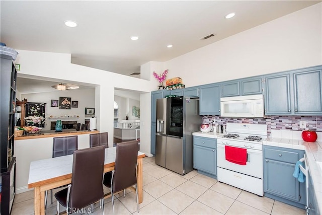 kitchen featuring blue cabinets, white appliances, visible vents, and tile countertops