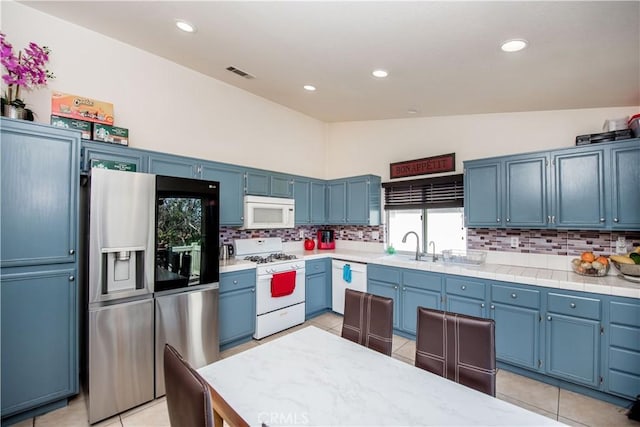 kitchen featuring lofted ceiling, white appliances, visible vents, and decorative backsplash