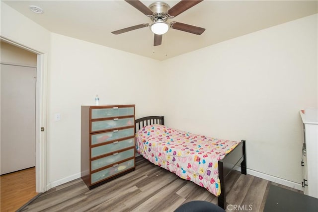 bedroom featuring a ceiling fan, baseboards, and wood finished floors