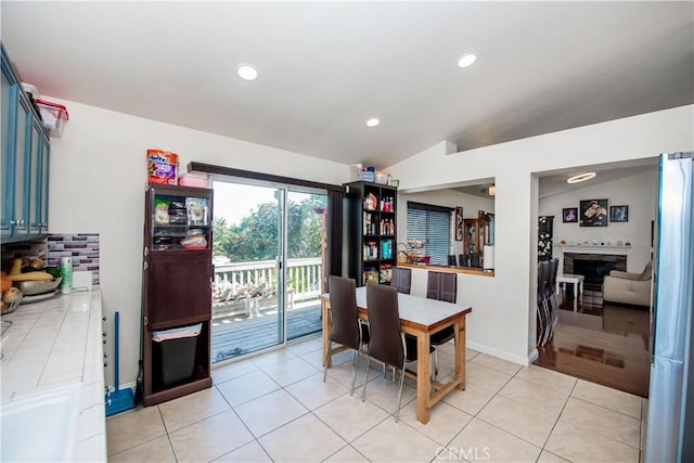 dining space featuring light tile patterned flooring, recessed lighting, a fireplace, baseboards, and vaulted ceiling