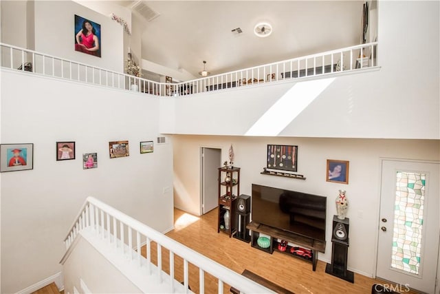 interior space featuring baseboards, visible vents, vaulted ceiling, and wood finished floors