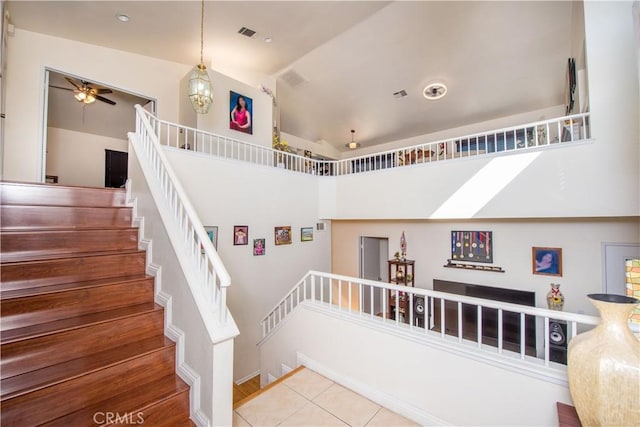 stairs featuring a ceiling fan, lofted ceiling, tile patterned flooring, and visible vents