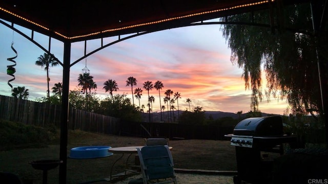 yard at dusk with a gazebo and fence