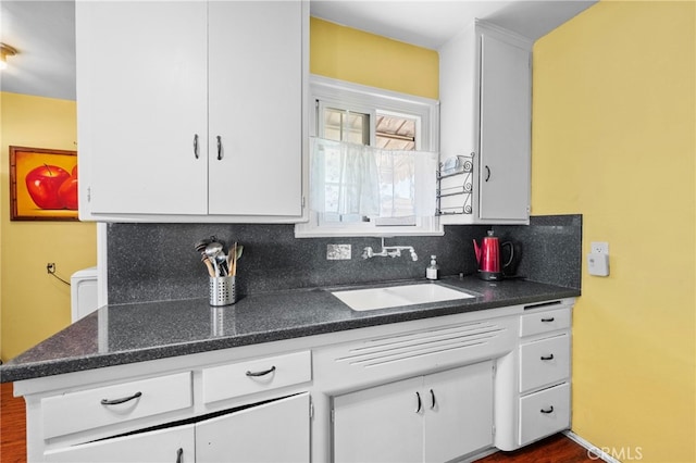 kitchen with backsplash, a sink, and white cabinetry