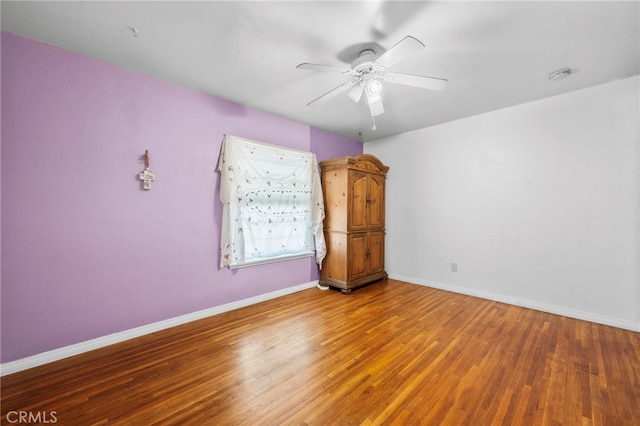 spare room with ceiling fan, baseboards, and wood finished floors