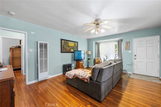 living area with a ceiling fan, baseboards, and wood finished floors