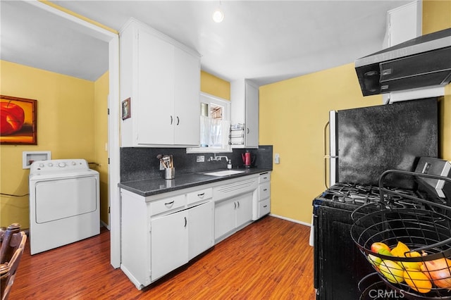 kitchen with a sink, freestanding refrigerator, decorative backsplash, washer / clothes dryer, and range with gas cooktop