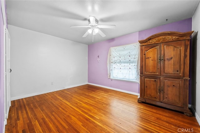 unfurnished bedroom featuring ceiling fan, baseboards, and wood finished floors