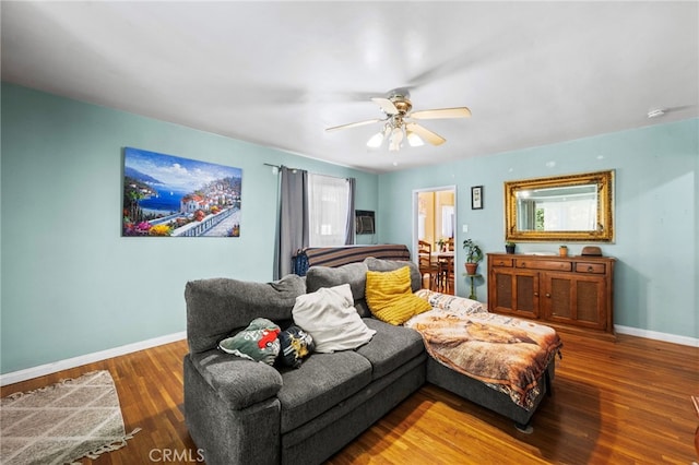 living room with a ceiling fan, baseboards, and wood finished floors