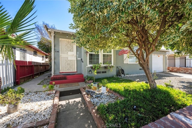 view of front of house with a garage, fence, and stucco siding