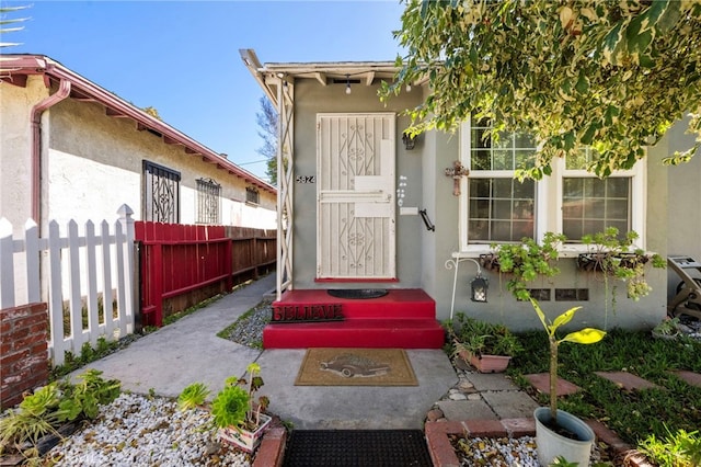 entrance to property with fence and stucco siding