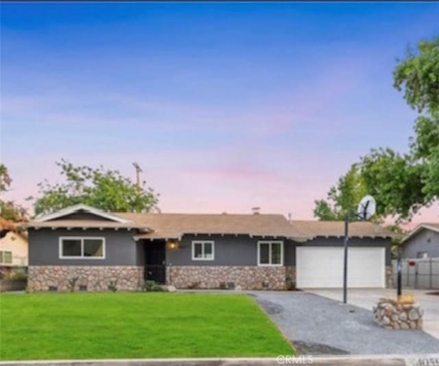 ranch-style home featuring driveway, a garage, fence, a yard, and stucco siding