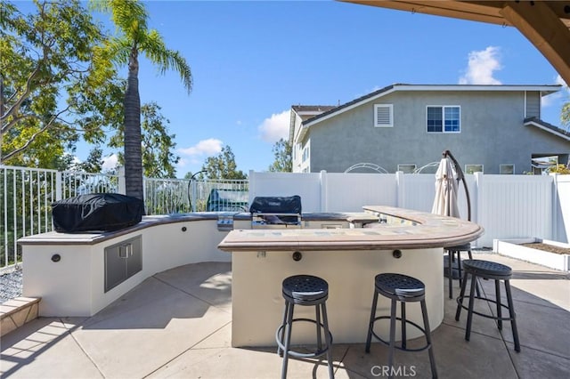 view of patio / terrace with area for grilling, a grill, outdoor wet bar, and a fenced backyard