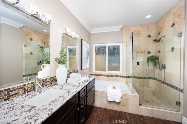 full bathroom featuring wood tiled floor, a shower stall, tiled tub, and a sink