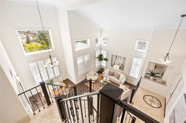 interior space with a chandelier, baseboards, crown molding, and a high ceiling