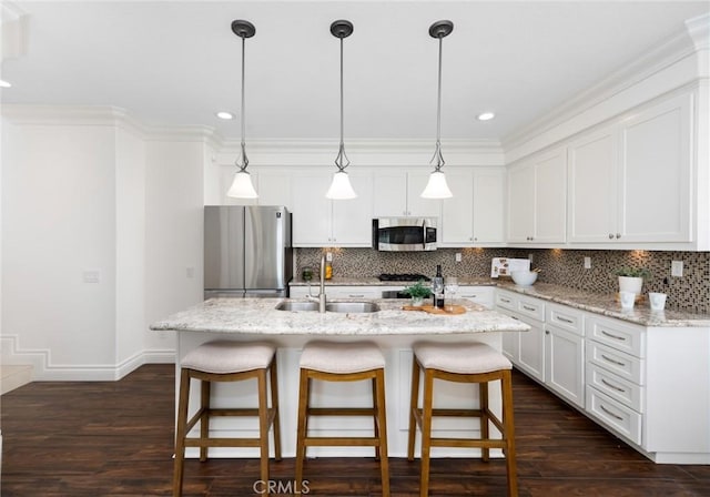 kitchen with dark wood finished floors, tasteful backsplash, appliances with stainless steel finishes, and a sink